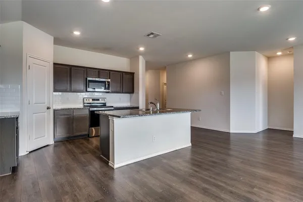 a kitchen with stainless steel appliances kitchen island granite countertop a stove a sink and a refrigerator