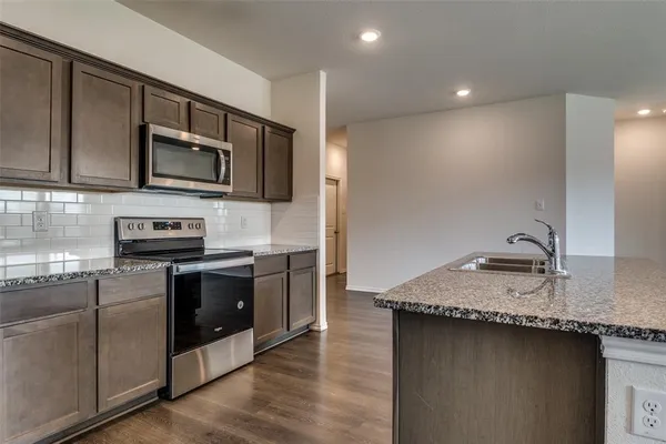 a kitchen with granite countertop a sink and a stove top oven