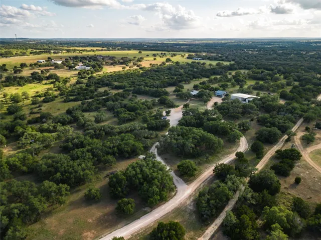 an aerial view of residential houses with outdoor space and trees