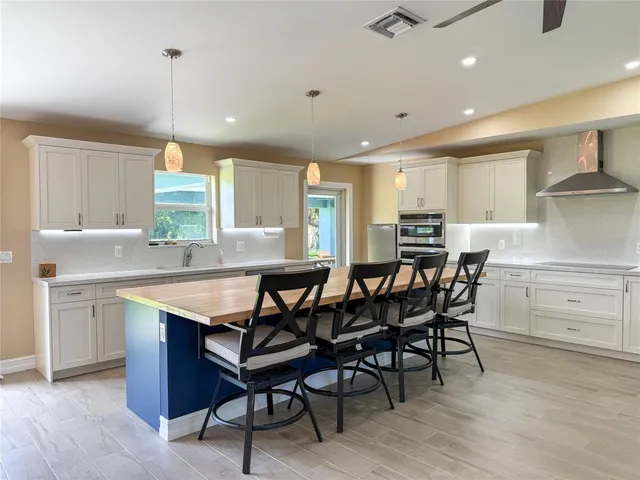 a kitchen with cabinets a sink dishwasher a dining table and chairs with wooden floor