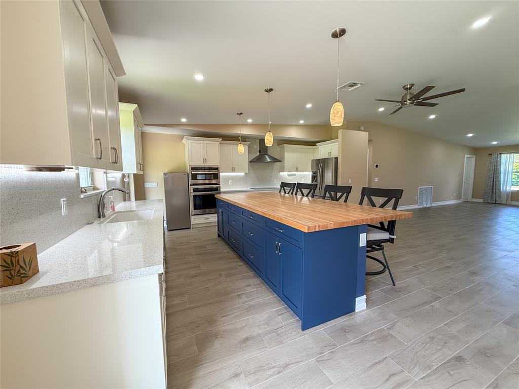 17420 Southwest 54th Street Southwest Ranches, FL 33331 - Photo 13 of 34 a large kitchen with stainless steel appliances kitchen island a large counter top and a view of living room