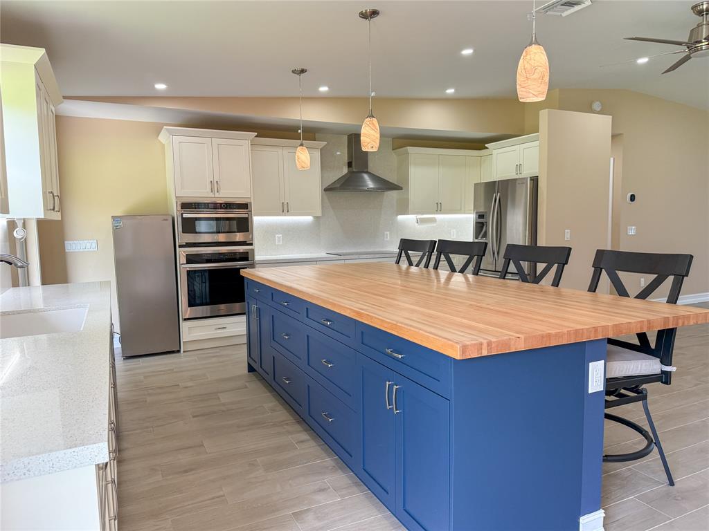 17420 Southwest 54th Street Southwest Ranches, FL 33331 - Photo 16 of 40 a kitchen with stainless steel appliances kitchen island granite countertop a table chairs in it and wooden floors