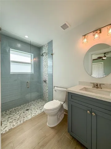 a bathroom with a granite countertop sink toilet a mirror and shower