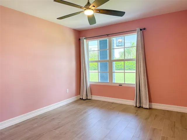 an empty room with wooden floor fan and windows