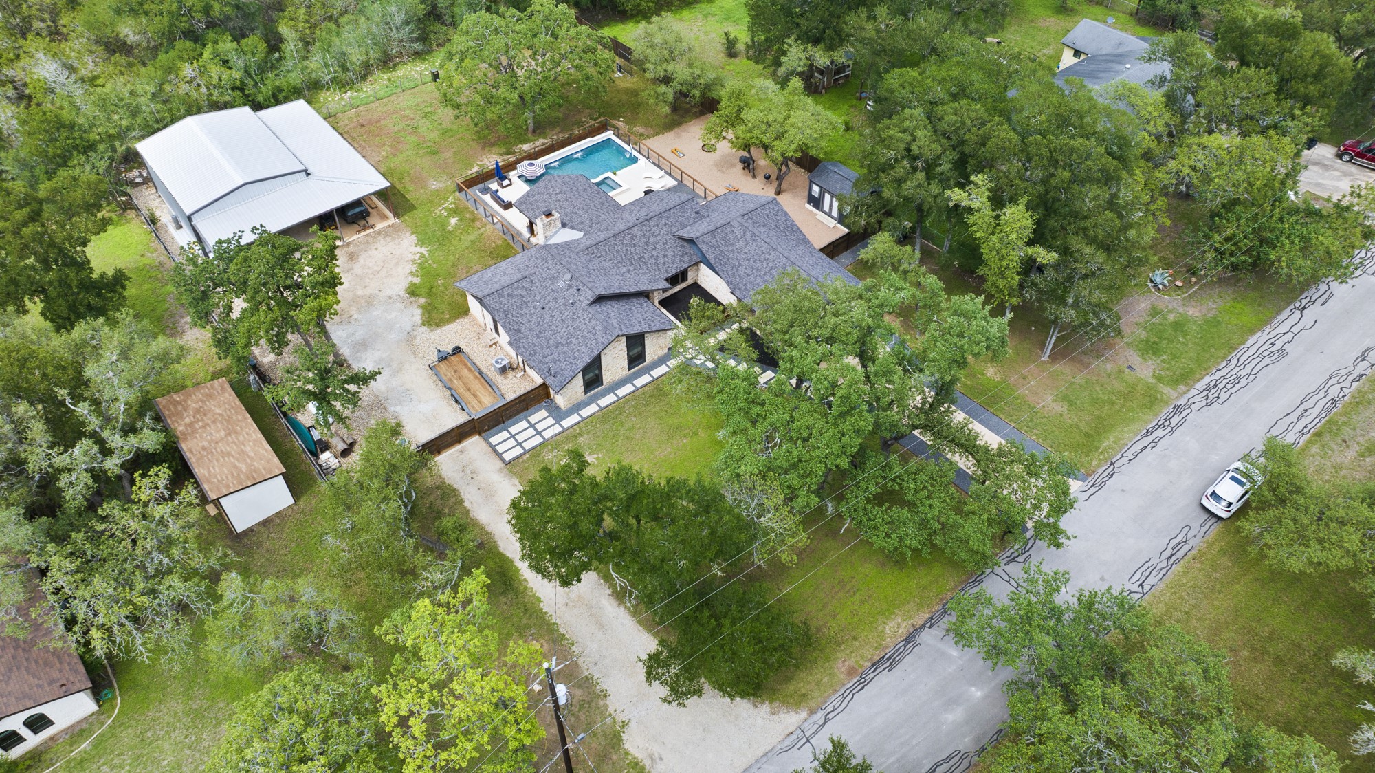 2802 Robin Road Manchaca, TX 78652 - Photo 39 of 40 Contemporary residence featuring a dark shingle roof, light-toned exterior siding, and an in-ground swimming pool