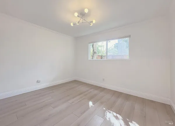 a view of an empty room with window and wooden floor