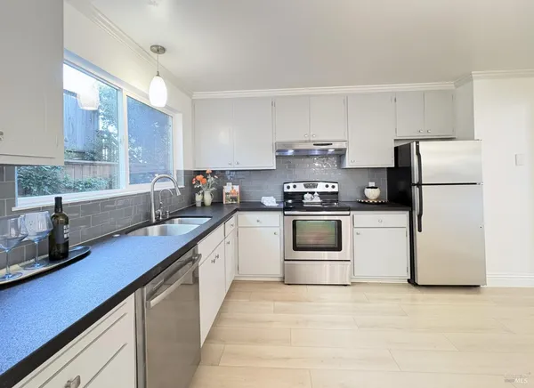 a kitchen with stainless steel appliances kitchen island granite countertop a table chairs stove and refrigerator