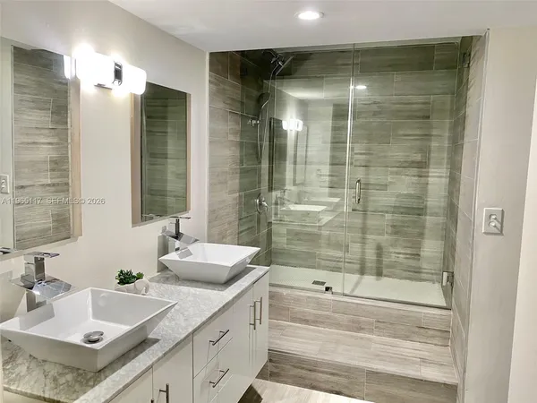 a bathroom with a double vanity sink mirror and shower