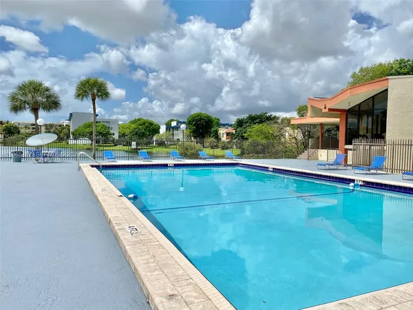 a view of swimming pool that has lawn chairs and a dining table under an umbrella