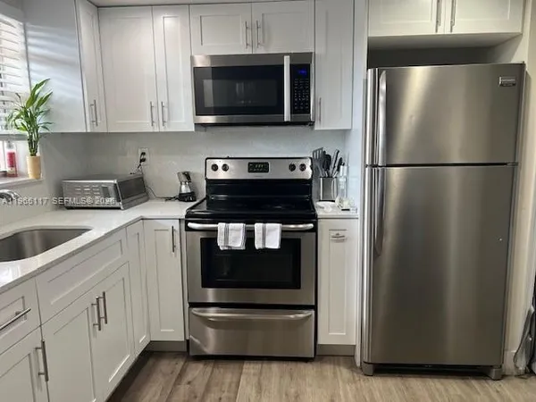 a kitchen with a refrigerator stove and white cabinets