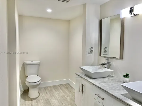 a bathroom with a granite countertop sink a toilet and a mirror