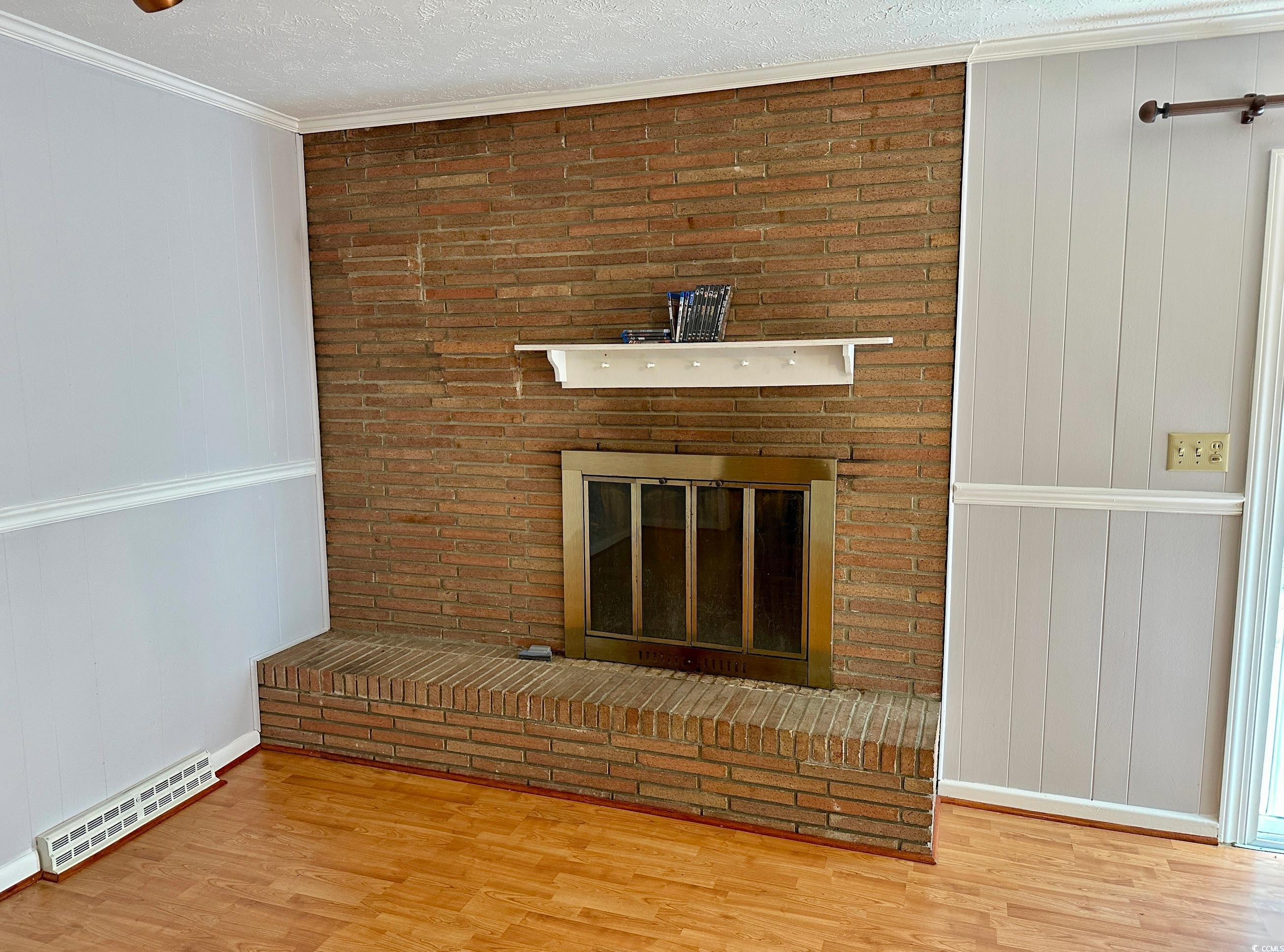601 Jefferson Street Bennettsville, SC 29512 - Photo 18 of 20 Detailed view of crown molding, a wood burning fireplace, a textured ceiling, wood finished floors, and wood walls