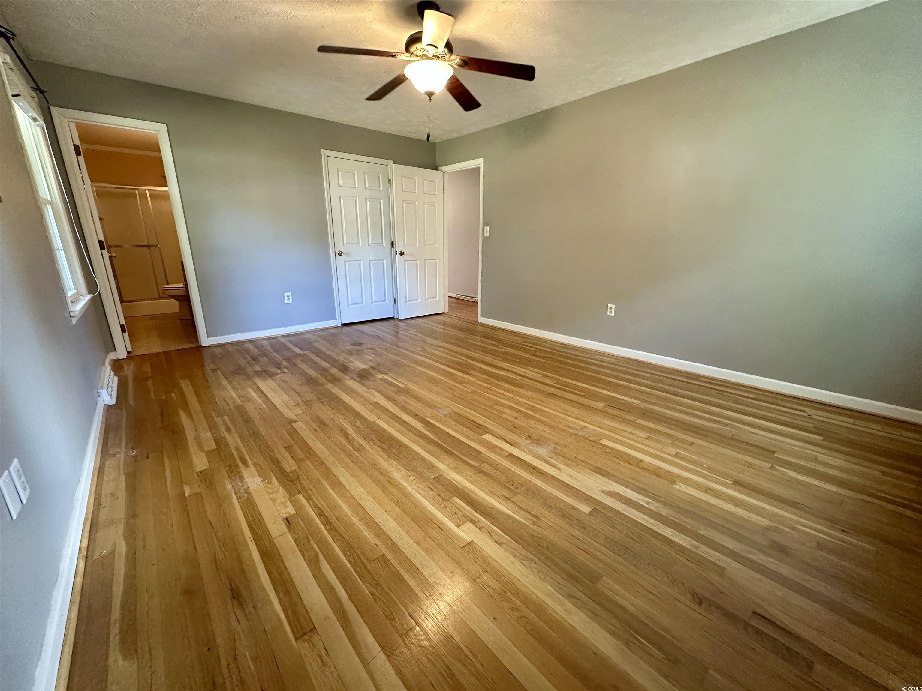 601 Jefferson Street Bennettsville, SC 29512 - Photo 20 of 20 Unfurnished bedroom with light hardwood flooring, a textured ceiling, a ceiling fan, and ensuite bathroom