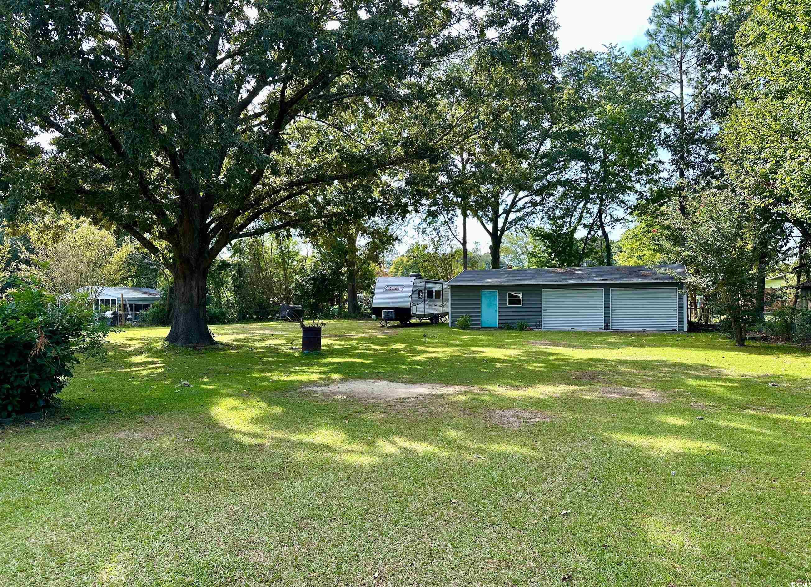 601 Jefferson Street Bennettsville, SC 29512 - Photo 3 of 20 View of grassy yard with an outdoor structure, a garage, and view of scattered trees