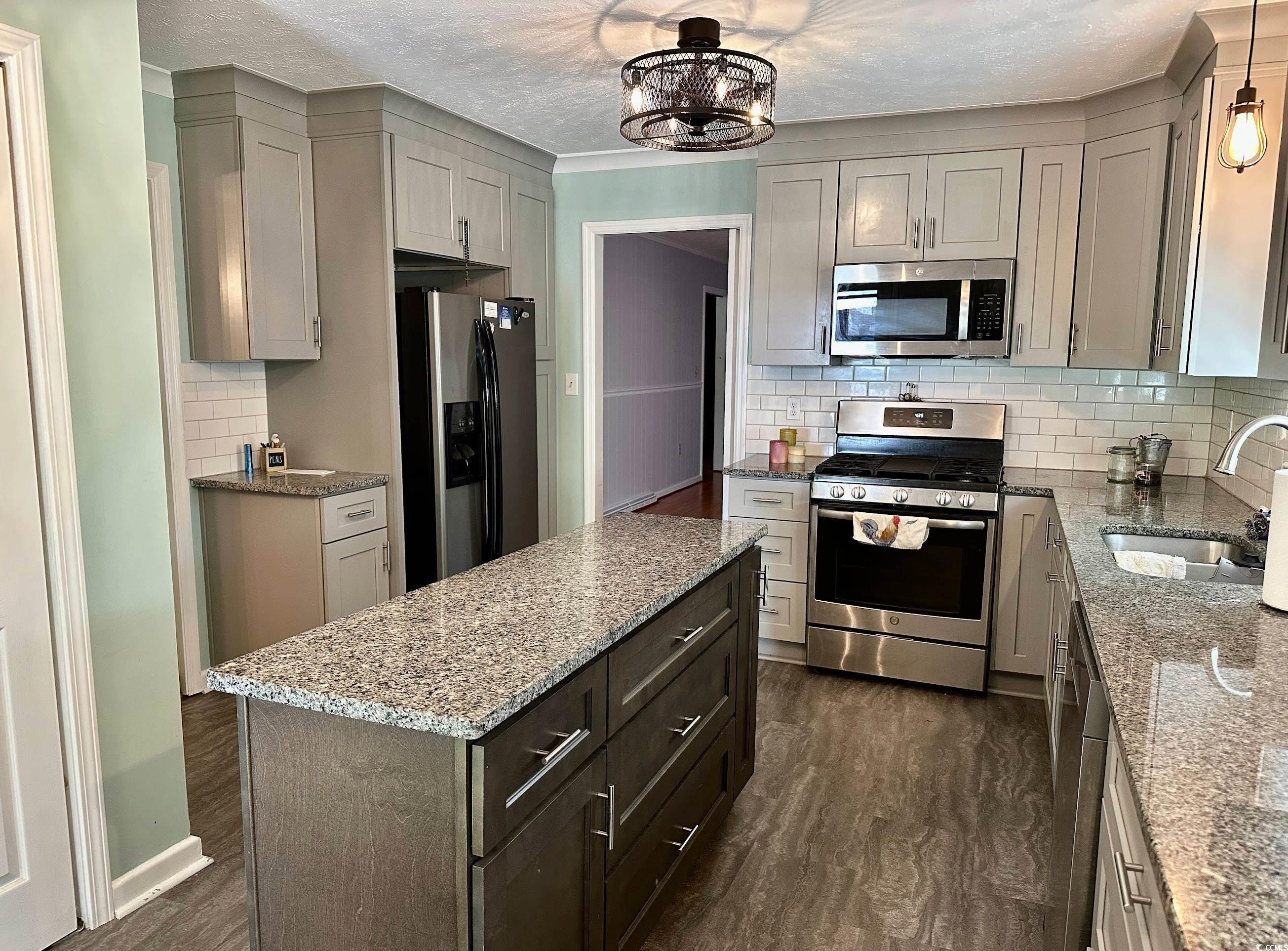 601 Jefferson Street Bennettsville, SC 29512 - Photo 8 of 20 Kitchen with appliances with stainless steel finishes, dark wood-type flooring, a center island, light stone counters, and a textured ceiling
