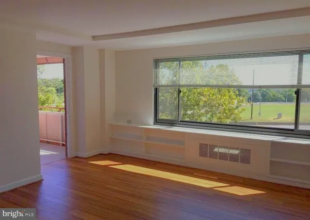 a view of an empty room with wooden floor and a window