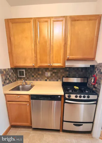 a utility room with stainless steel appliances wooden cabinets and a stove top oven