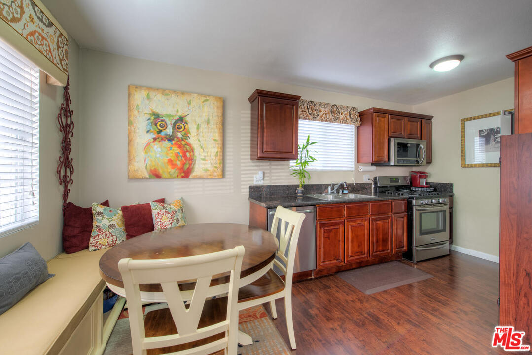 10541 Chandler Boulevard North Hollywood, CA 91601 - Photo 6 of 17 a kitchen with stainless steel appliances granite countertop a stove a sink a microwave a dining table and chairs with wooden floor