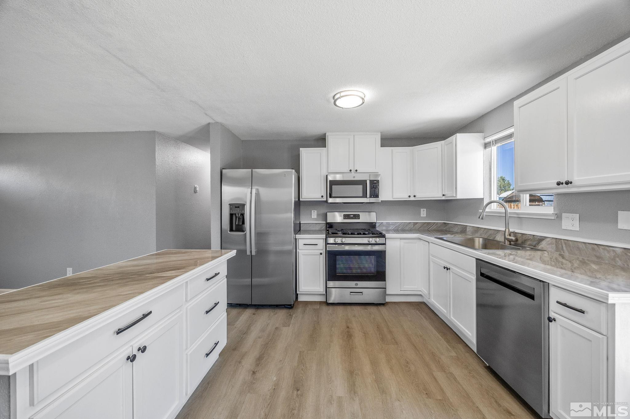 10069 Basalt Court Reno, NV 89506 - Photo 9 of 30 a kitchen with stainless steel appliances granite countertop a stove a sink dishwasher a refrigerator and white cabinets with wooden floor