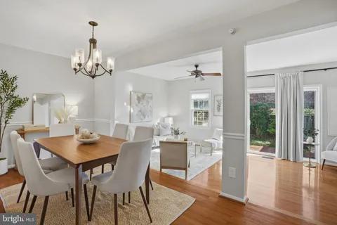 a dining room with wooden floor a chandelier a wooden table and chairs
