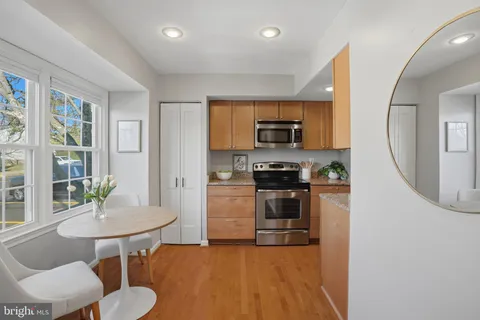 a kitchen with stainless steel appliances a dining table chairs and stove top oven