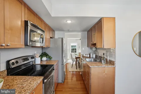 a kitchen with granite countertop a stove a sink a refrigerator and cabinets