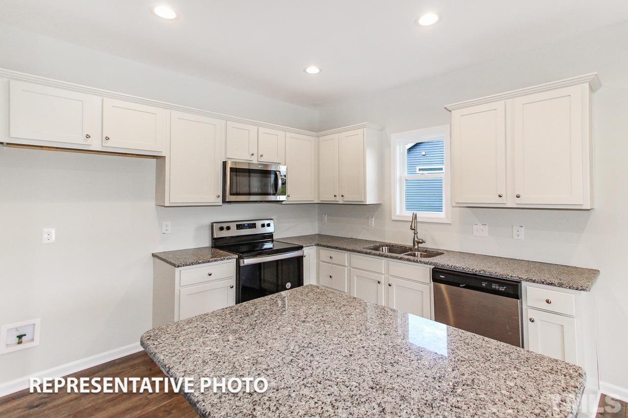 67 Weathervane Dr. Zebulon, NC 27597 - Photo 4 of 10 a kitchen with granite countertop a stove sink and cabinets