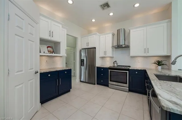 a large kitchen with stainless steel appliances granite countertop a refrigerator and a stove top oven