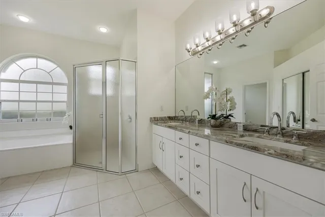 a spacious bathroom with a granite countertop sink a mirror and a bathtub