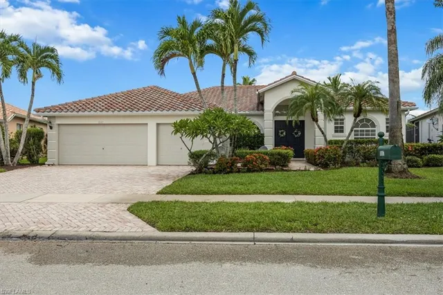 a front view of a house with a garden and palm trees