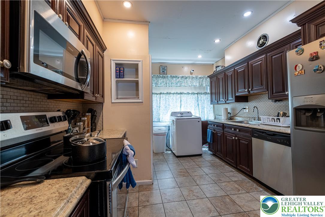 118 South 3rd Street Bangor, PA 18013 - Photo 8 of 33 This kitchen features rich cabinetry, practical appliances, and durable tiled flooring.