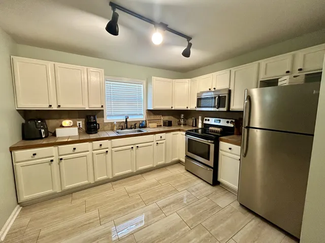 a kitchen with stainless steel appliances granite countertop a refrigerator a stove a sink and a microwave