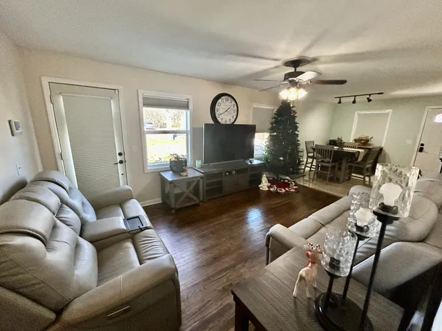 a living room with furniture a large window and a wooden floor