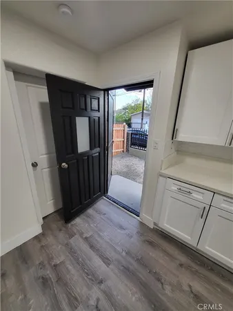 a view of a hallway to a livingroom with wooden floor and furniture