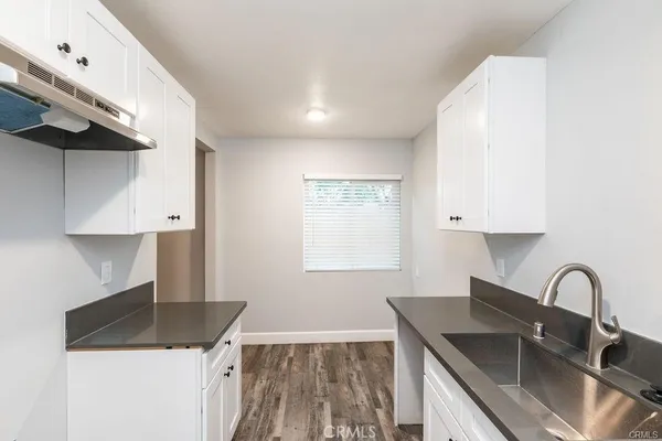 a kitchen with granite countertop a sink a stove and a wooden floor