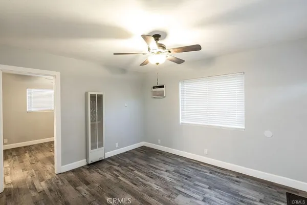 a view of an empty room with a window and wooden floor