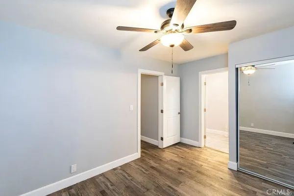 a view of an empty room with wooden floor and a ceiling fan