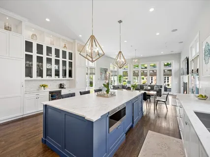 a large kitchen with kitchen island a stove a sink a oven a dining table and chairs