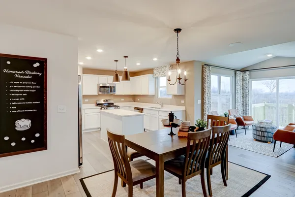 a view of a dining room and livingroom with furniture wooden floor and windows