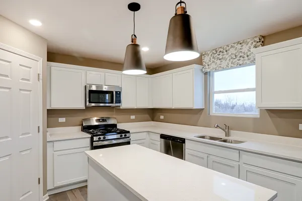 a kitchen with stainless steel appliances a sink a stove a refrigerator and white cabinets