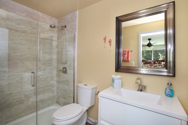 1697 Pe'e Road, Unit 104 Koloa, HI 96756 - Photo 9 of 17 a bathroom with a toilet sink vanity and shower