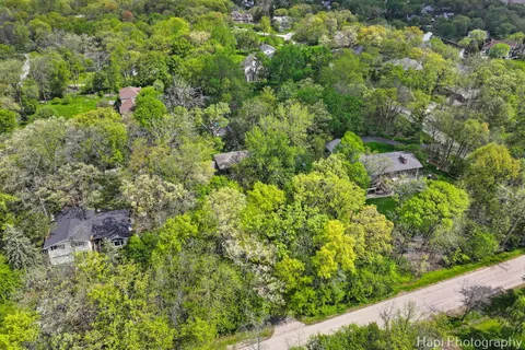 an aerial view of residential house with outdoor space and trees all around