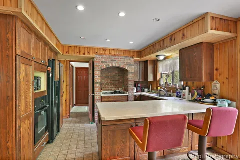 a kitchen with sink a refrigerator and chairs