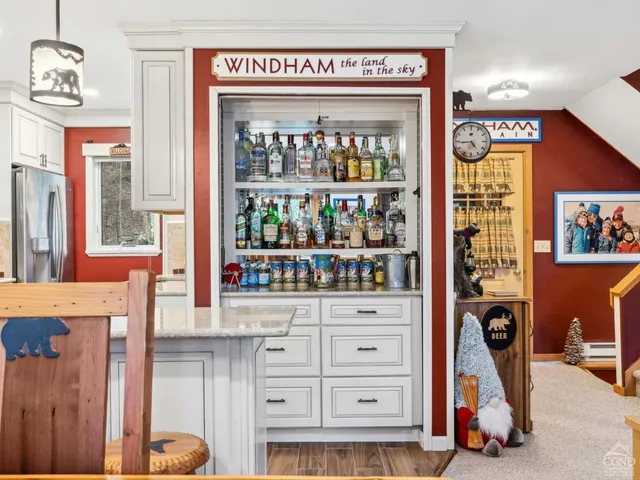 a kitchen with stainless steel appliances granite countertop a stove top oven a sink a dining table and chairs with wooden floor