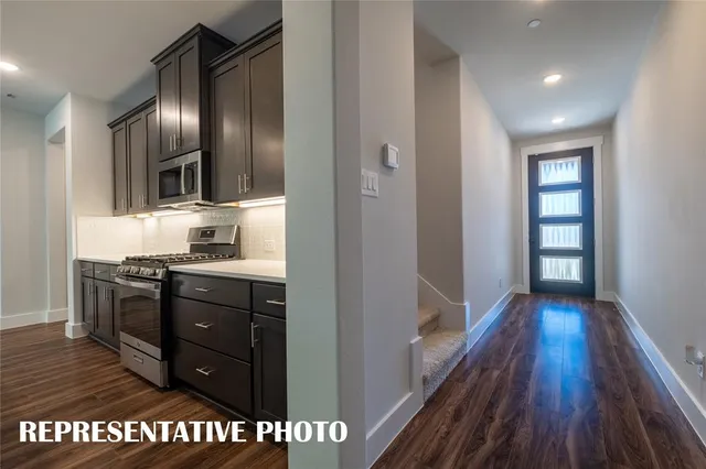 a kitchen with granite countertop stainless steel appliances and wooden floor