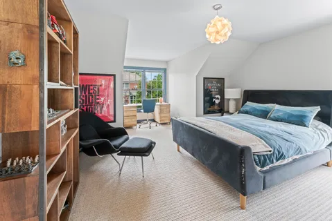 a spacious bedroom with a bed dresser and a chandelier