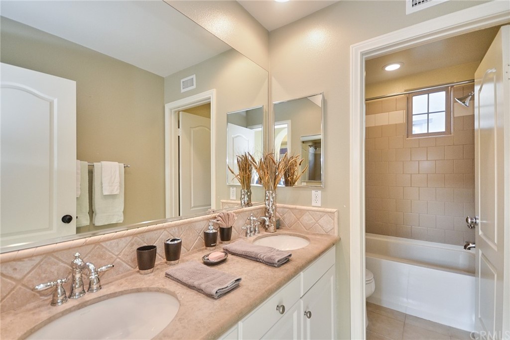 39 Conservancy Irvine, CA 92618 - Photo 14 of 32 a bathroom with a granite countertop sink double mirror and a bathtub