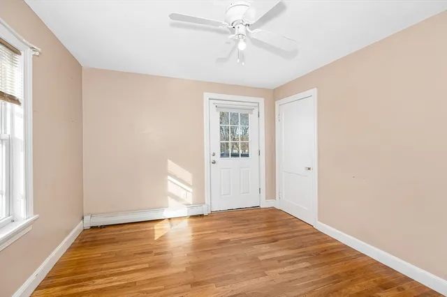 a view of empty room with wooden floor and fan