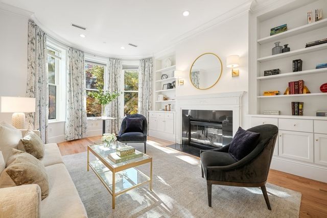 a living room with furniture a fireplace a rug and a large window