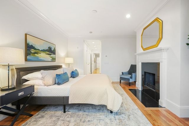 a bedroom with a bed a fireplace and a painting on the wall